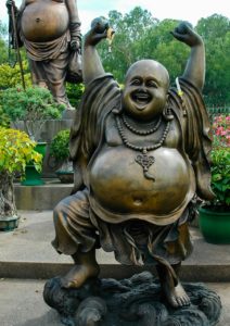 fröhlicher Bronze-Budda streckt die Arme in den Himmel